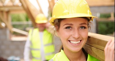 En kvinnlig och en manlig byggnadsarbetare på en byggarbetsplats