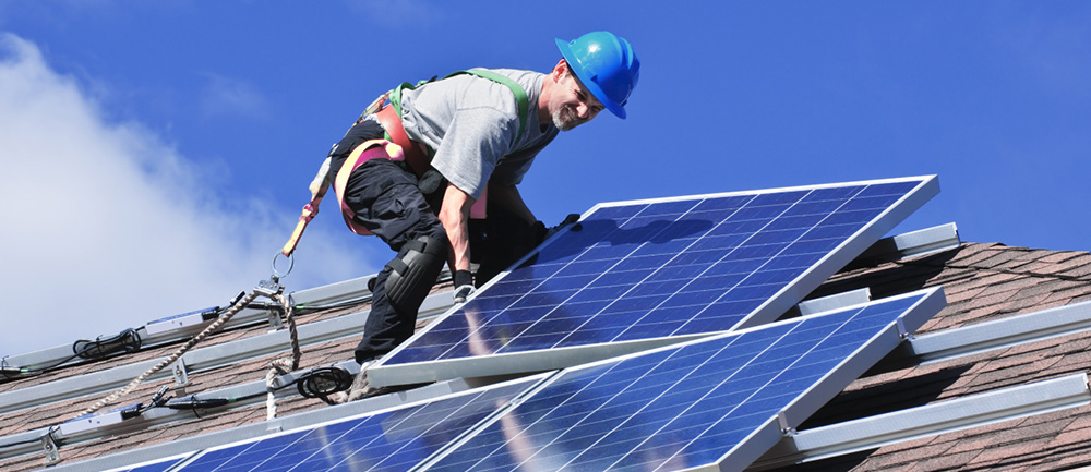 En man installerar solpaneler på ett tak. 